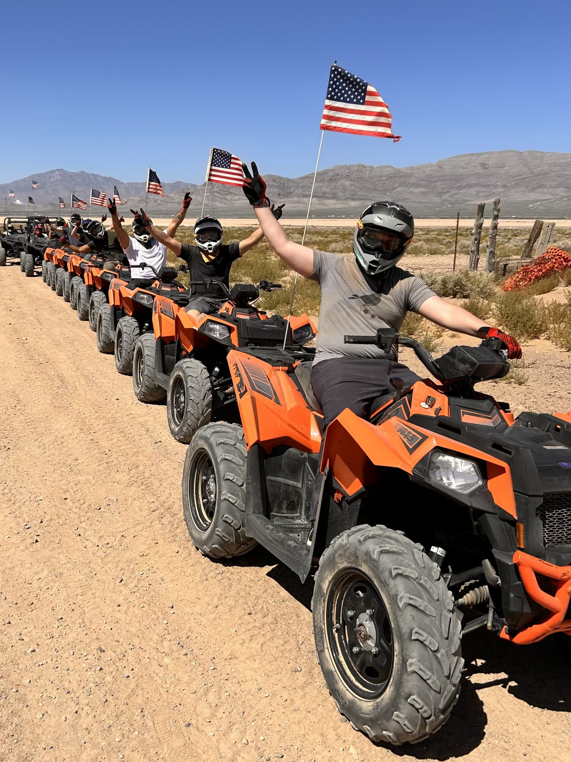 A group of people riding atvs down the middle of a dirt road.