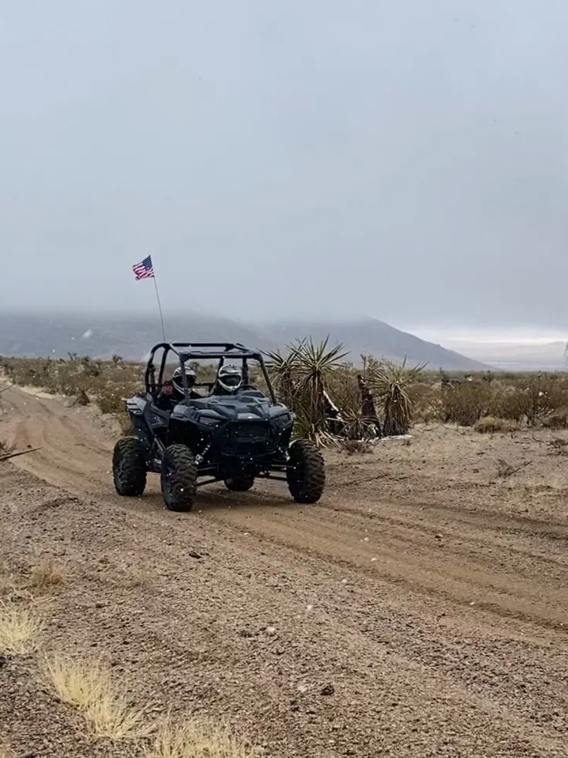 A black buggy driving down the road in the desert.