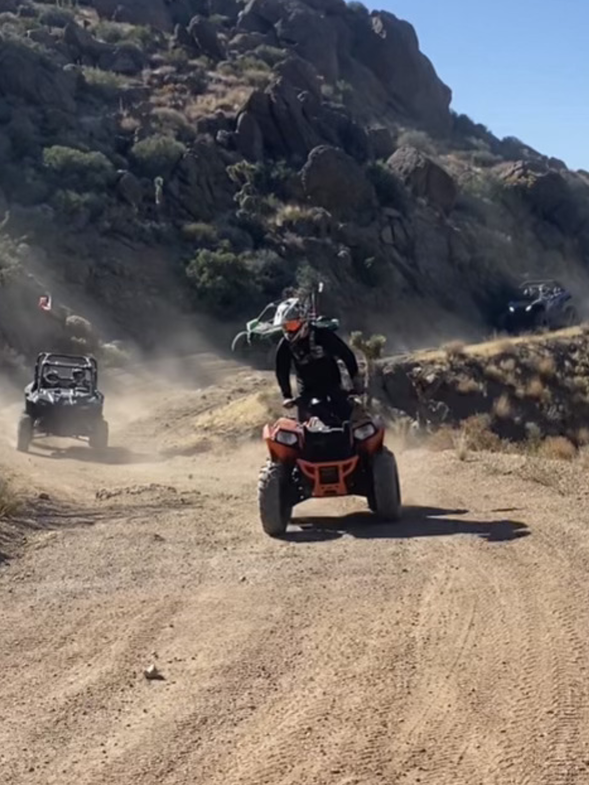 A man riding an atv on top of a dirt road.